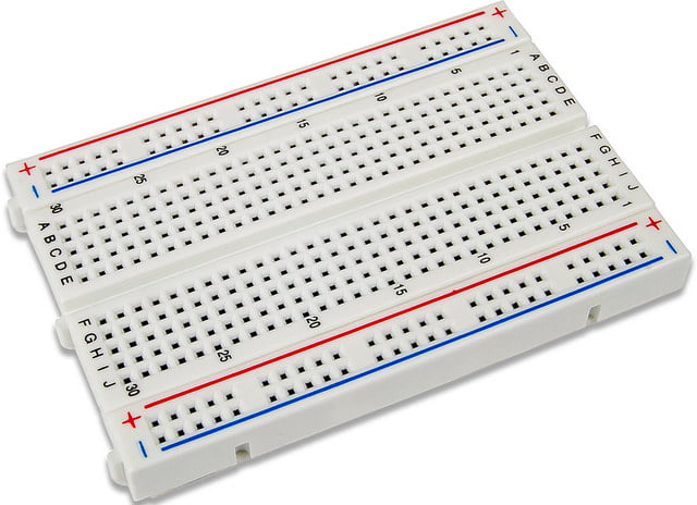 Close-up of a breadboard showing power rails, terminal strips, and labeled rows and columns for electronic prototyping